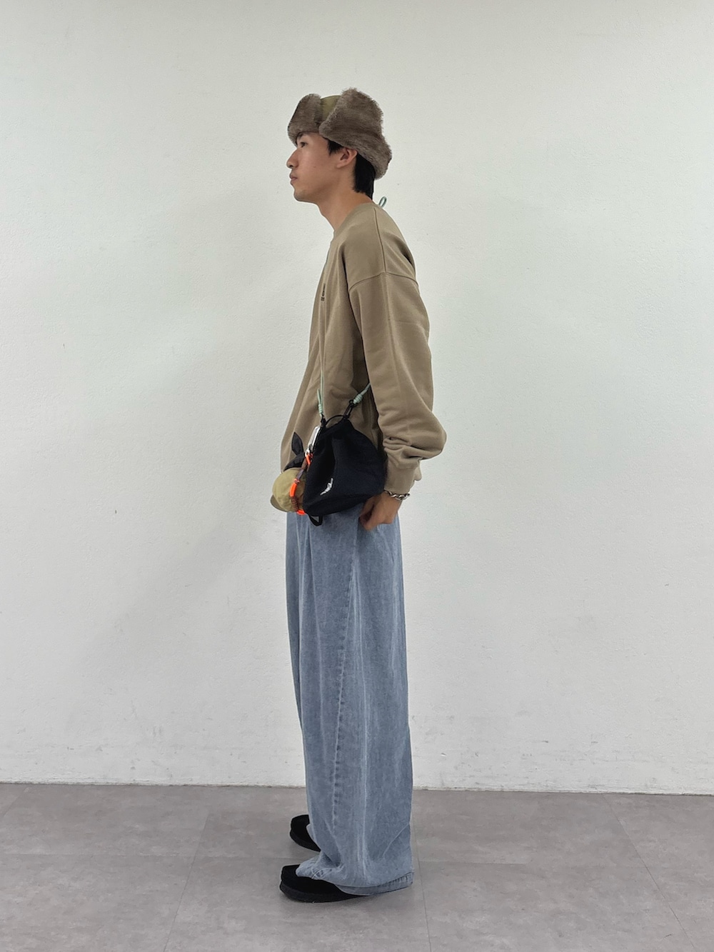 ベージュ系のスウェット、ブラック系のトートバッグ、ブルー系のデニムパンツを着用したメンズの秋コーディネートの2枚目の写真