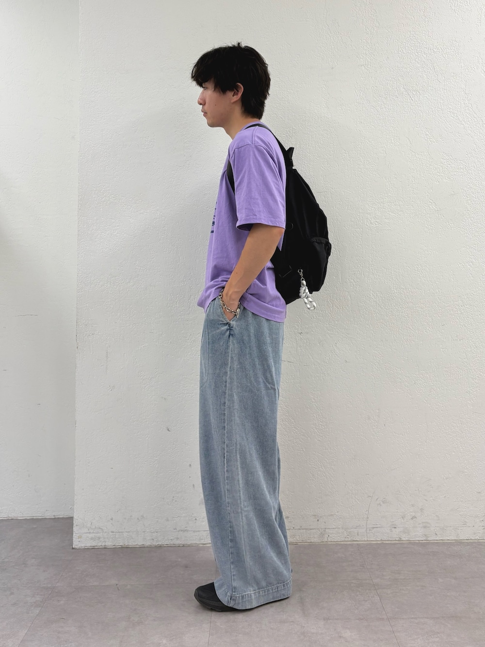 パープル系のTシャツ/カットソー、ブルー系のデニムパンツ、ブラック系のバックパック/リュックを着用したメンズの夏コーディネートの2枚目の写真