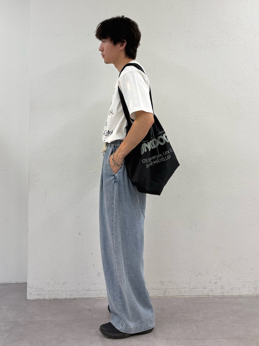 ホワイト系のTシャツ/カットソー、ブラック系のトートバッグ、ブルー系のデニムパンツを着用したメンズの夏コーディネートの2枚目の写真