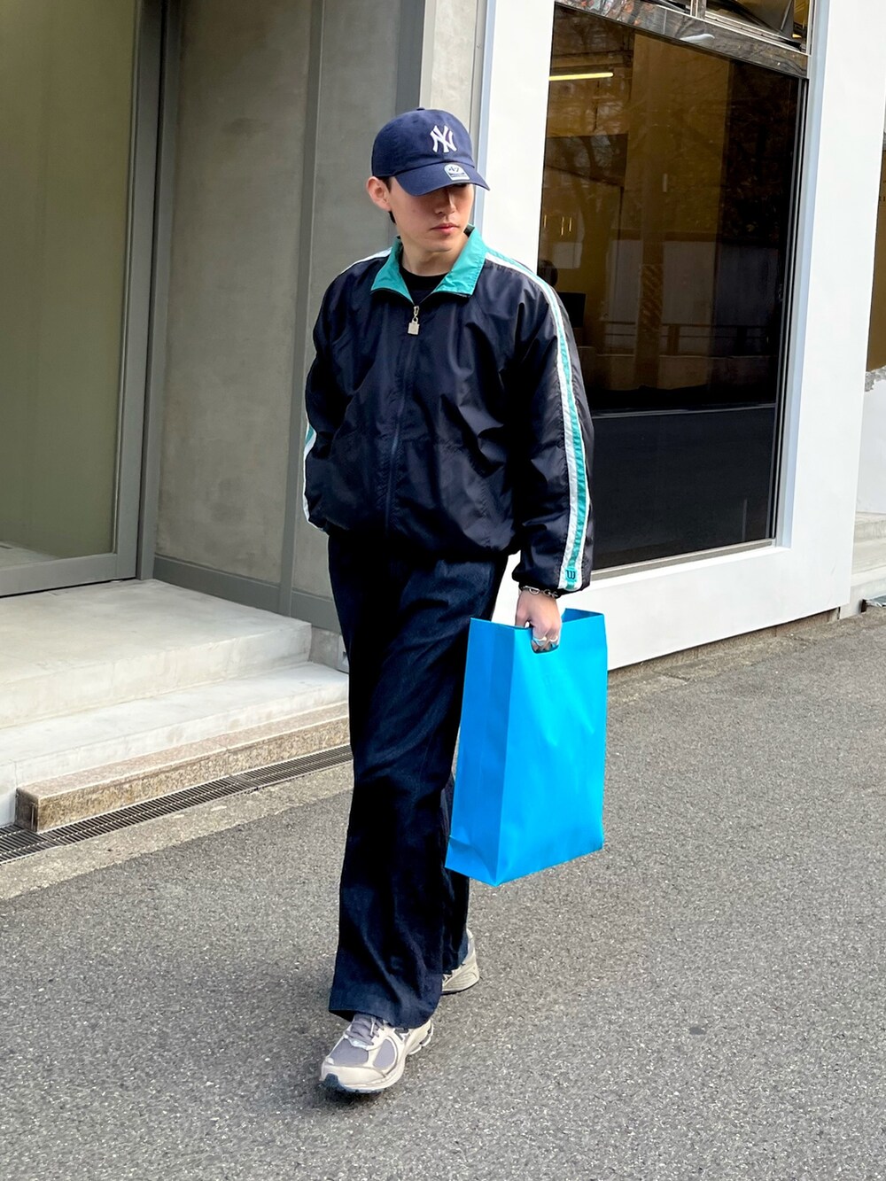 グレー系のスニーカー、ブルー系のデニムパンツ、ブラック系のナイロンジャケットを着用したメンズの冬コーディネートの2枚目の写真