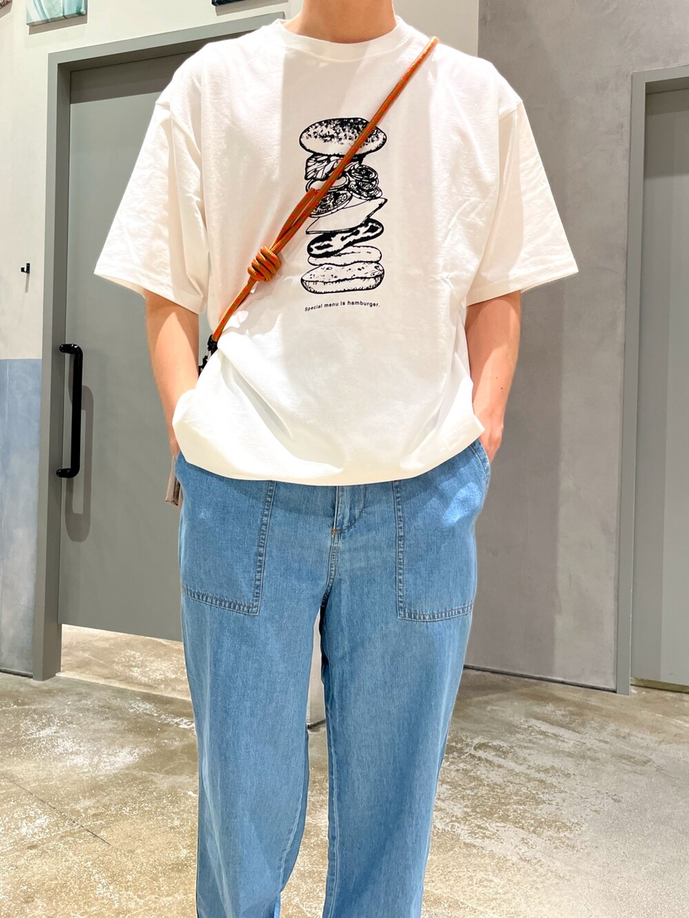 ブルー系のデニムパンツ、ブラック系のスニーカー、ブラック系のショルダーバッグを着用したメンズの夏コーディネートの3枚目の写真