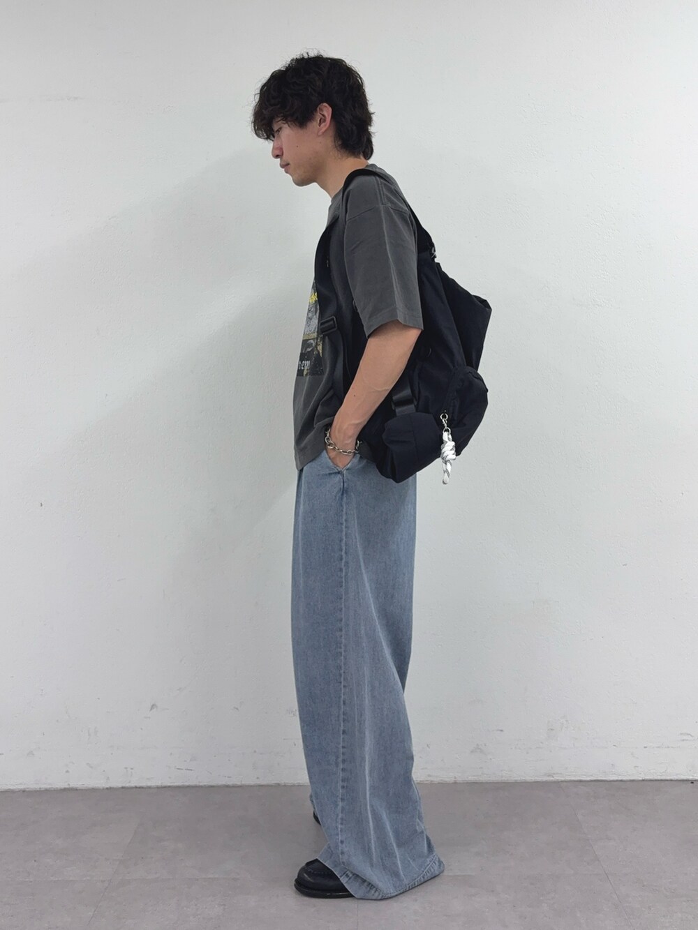 ブラック系のTシャツ/カットソー、ブラック系のバックパック/リュック、ブルー系のデニムパンツを着用したメンズの夏コーディネートの2枚目の写真