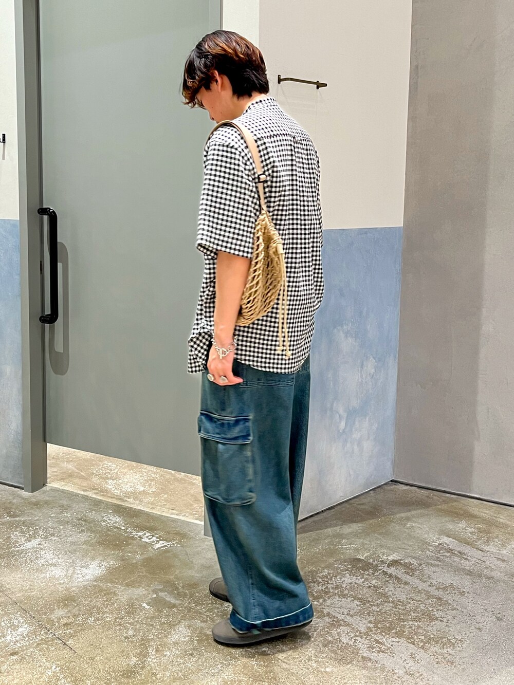 ブルー系のカーゴパンツ、グレー系のスニーカー、ベージュ系のショルダーバッグを着用したメンズの夏コーディネートの2枚目の写真