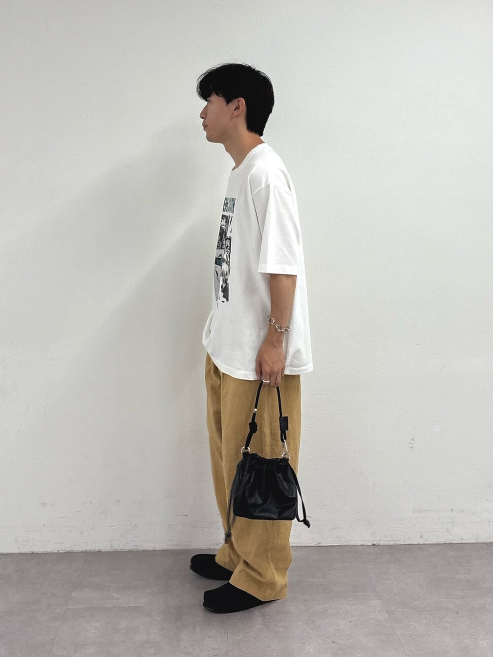 ホワイト系のTシャツ/カットソー、ブラック系のショルダーバッグ、ベージュ系のチノパンツを着用したメンズの夏コーディネートの2枚目の写真