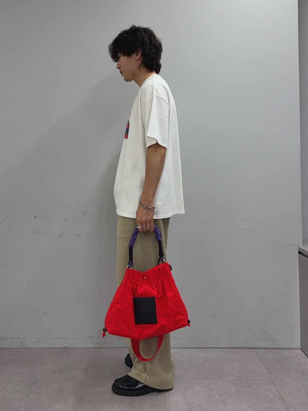ホワイト系のTシャツ/カットソー、ベージュ系のスウェットパンツ、レッド系のトートバッグを着用したメンズの夏コーディネートの2枚目の写真
