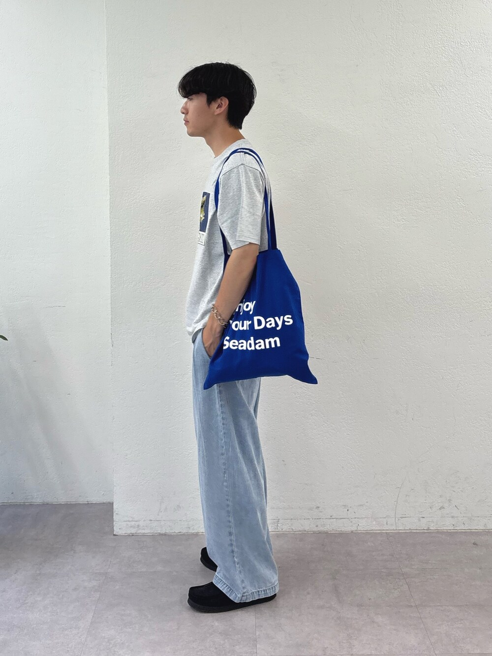 グレー系のTシャツ/カットソー、ブルー系のトートバッグ、ブルー系のデニムパンツを着用したメンズの夏コーディネートの2枚目の写真