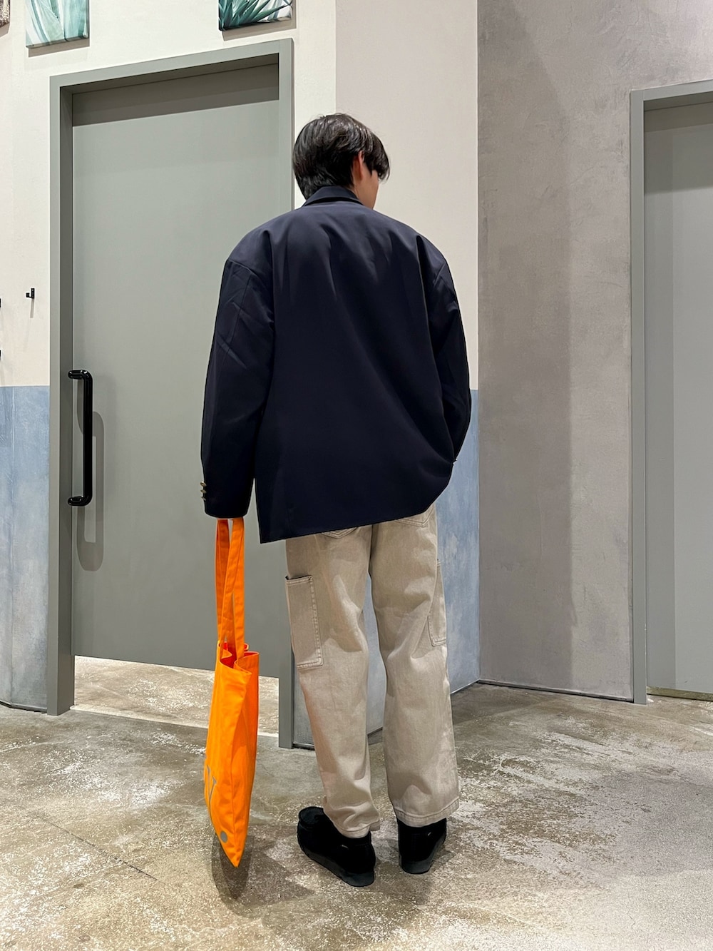 ブラック系のスニーカー、グレー系のデニムパンツ、オレンジ系のトートバッグを着用したメンズの春コーディネートの3枚目の写真