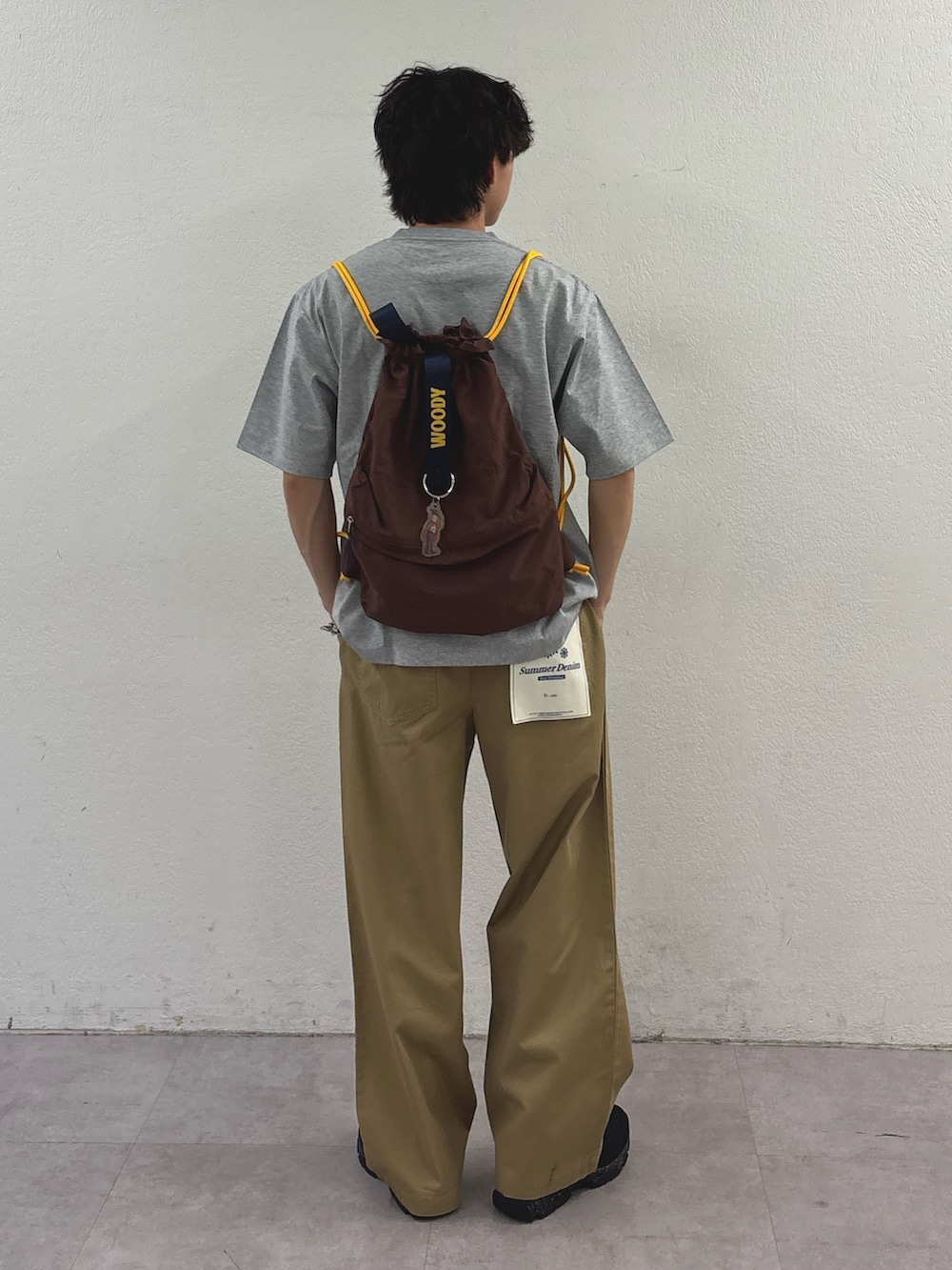 グレー系のTシャツ/カットソー、ブラウン系のバックパック/リュック、ベージュ系のデニムパンツを着用したメンズの春コーディネートの3枚目の写真