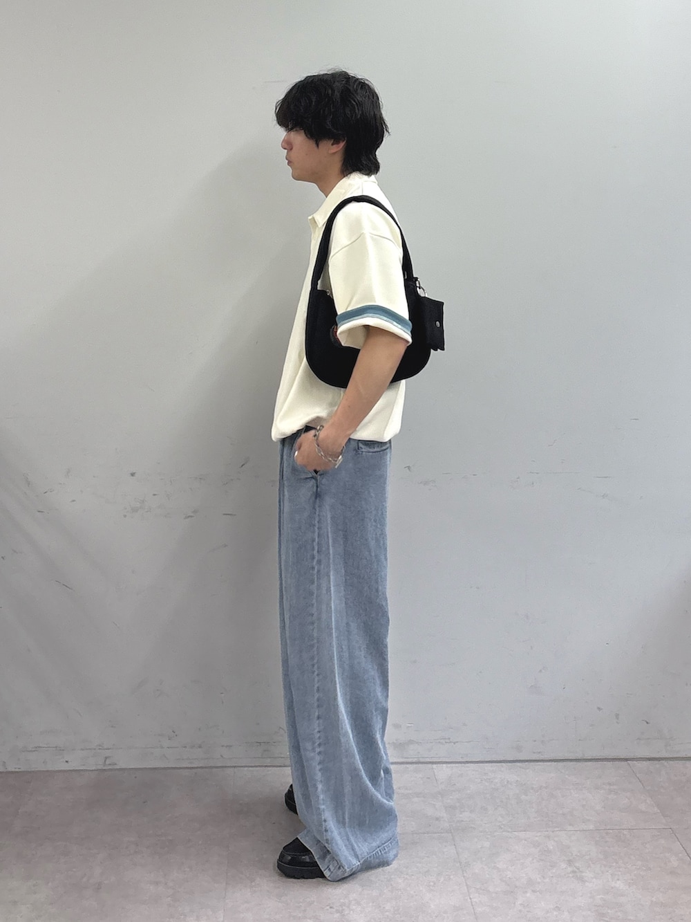 ホワイト系のポロシャツ、ブラック系のショルダーバッグ、ブルー系のデニムパンツを着用したメンズの春コーディネートの2枚目の写真