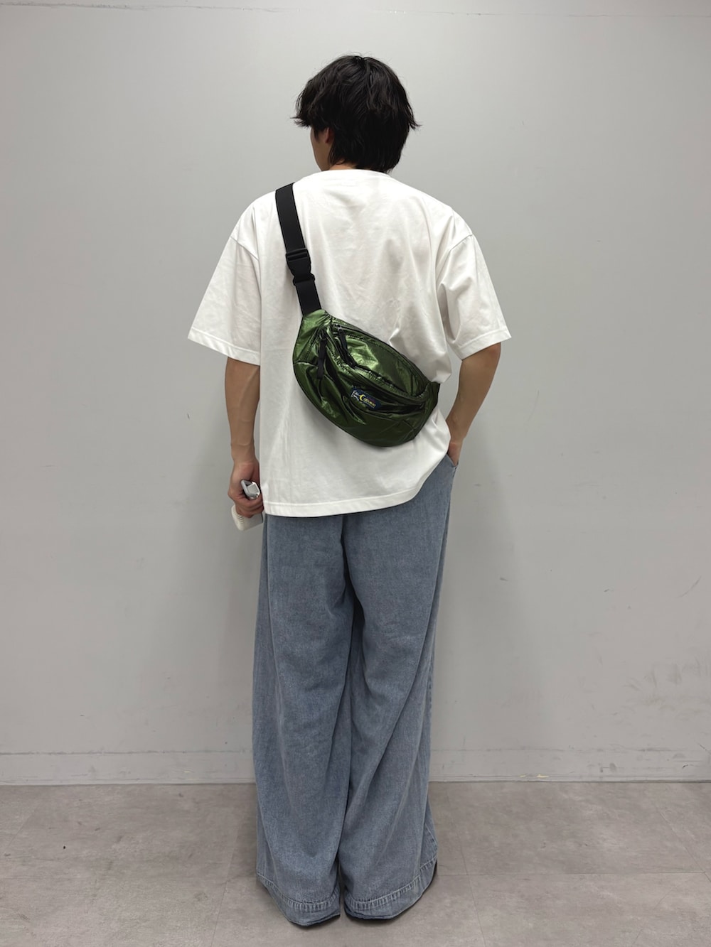 ブルー系のデニムパンツ、グリーン系のボディバッグ/ウエストポーチ、ホワイト系のTシャツ/カットソーを着用したメンズの春コーディネートの3枚目の写真