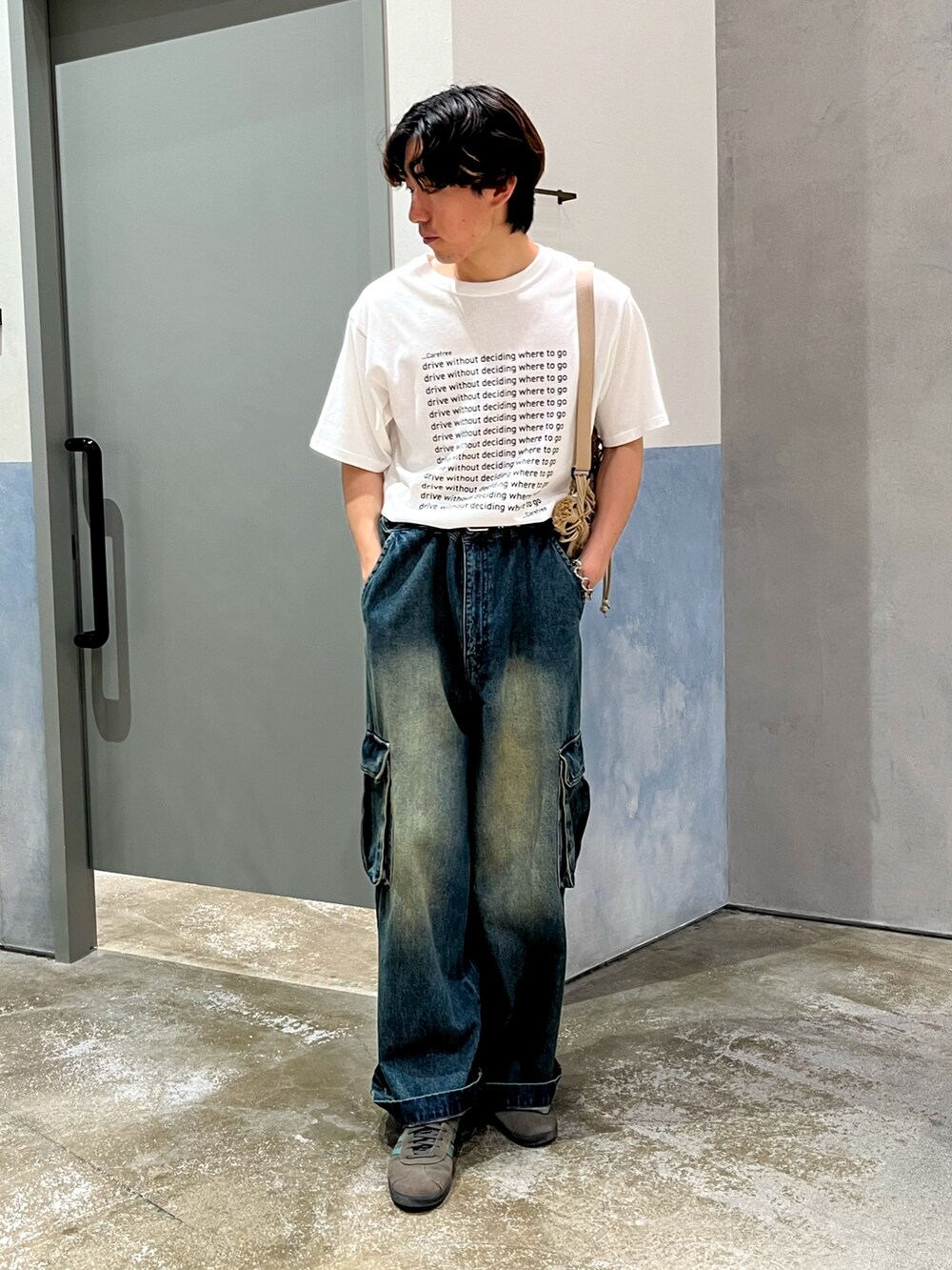 ブルー系のカーゴパンツ、グレー系のスニーカー、ベージュ系のショルダーバッグを着用したメンズの夏コーディネートの3枚目の写真