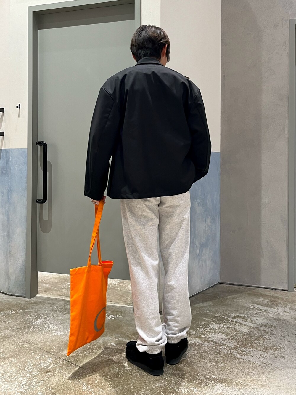 ブラック系のスニーカー、オレンジ系のトートバッグ、グレー系のスウェットパンツを着用したメンズの春コーディネートの2枚目の写真