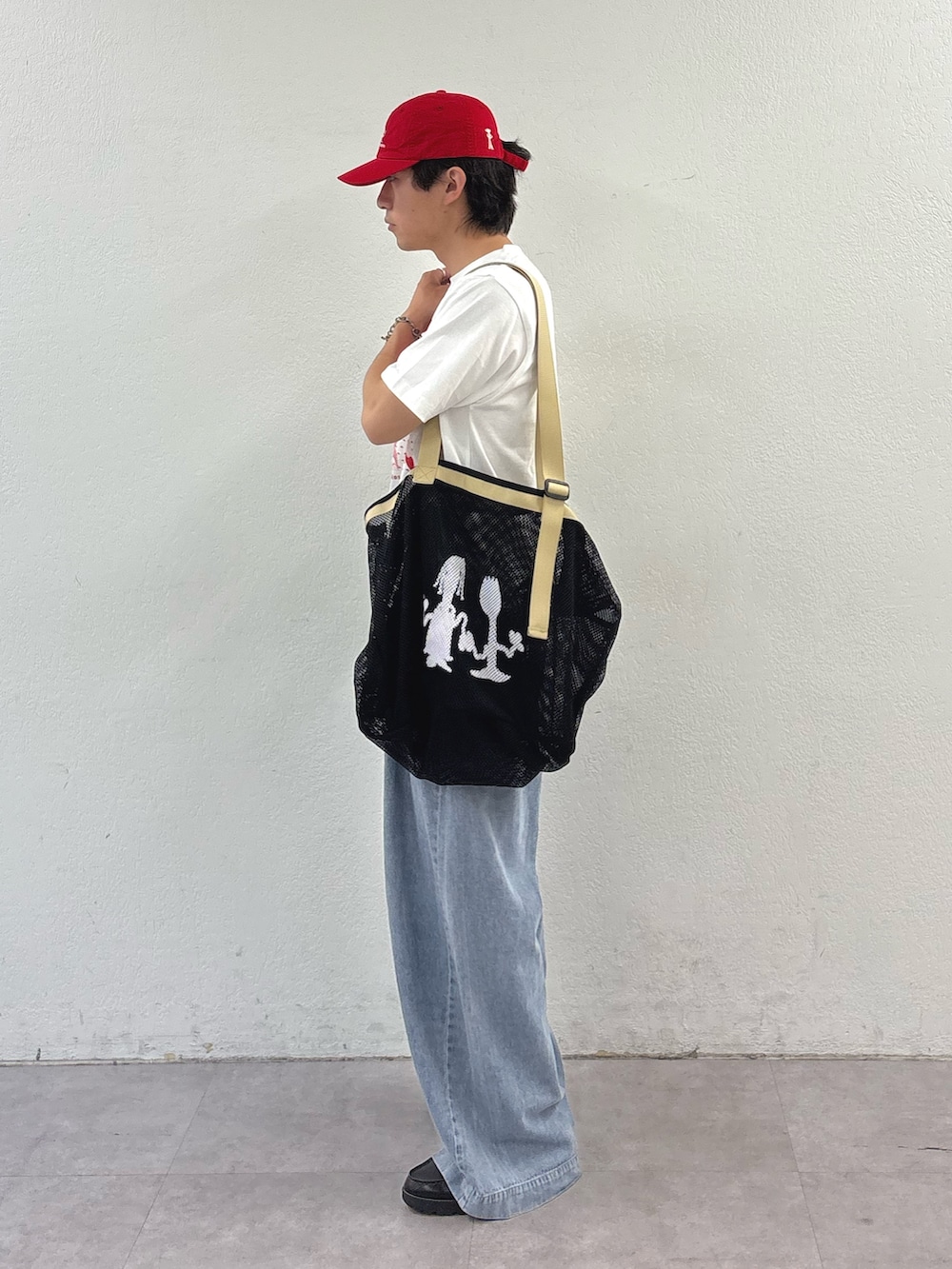 ホワイト系のTシャツ/カットソー、ブルー系のデニムパンツ、ブラック系のトートバッグを着用したメンズの春コーディネートの2枚目の写真