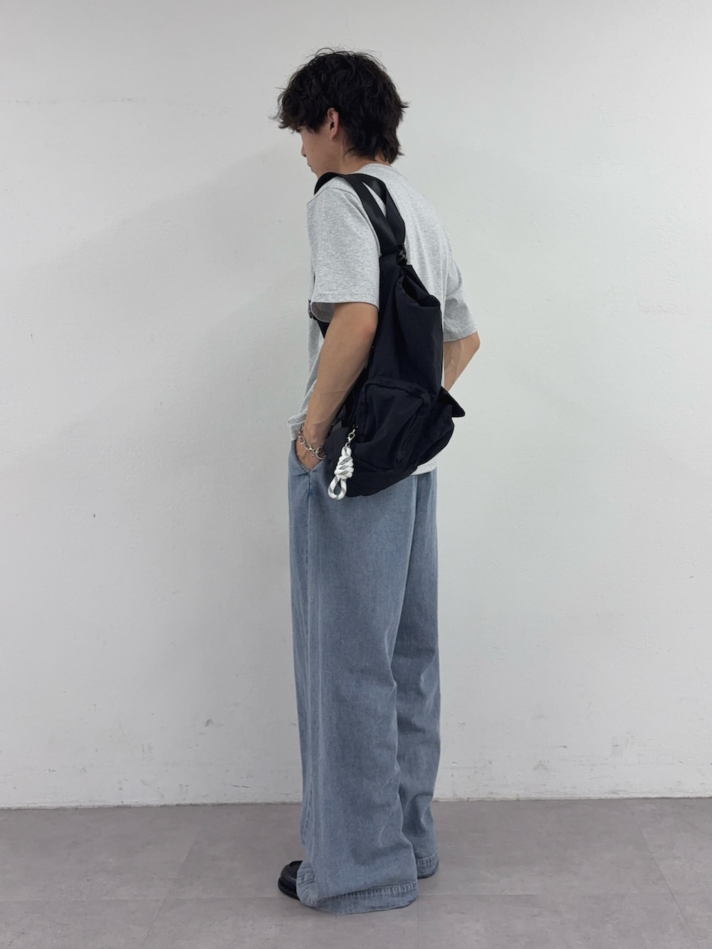 グレー系のTシャツ/カットソー、ブラック系のバックパック/リュック、ブルー系のデニムパンツを着用したメンズの夏コーディネートの2枚目の写真