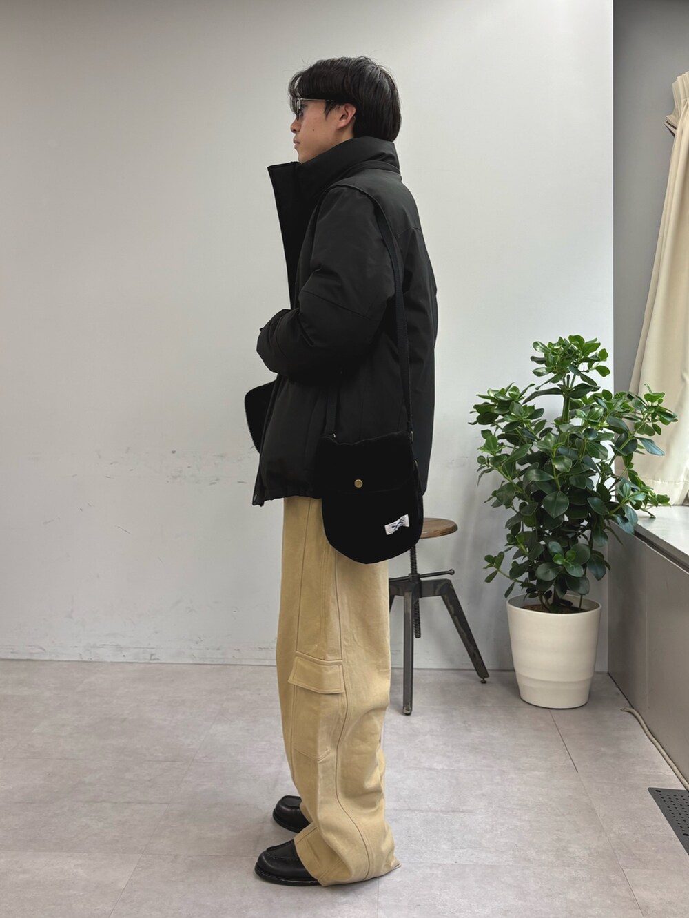 ブラック系のダウンジャケット/コート、ブラウン系のシャツ/ブラウス、ベージュ系のカーゴパンツを着用したメンズの冬コーディネートの2枚目の写真