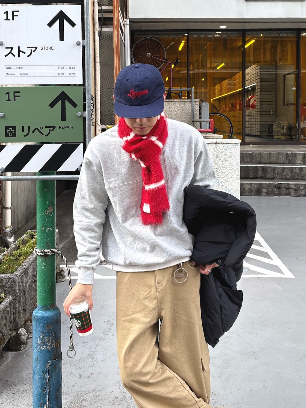 グレー系のスウェット、ベージュ系のデニムパンツ、レッド系のマフラーを着用したメンズの冬コーディネートの2枚目の写真