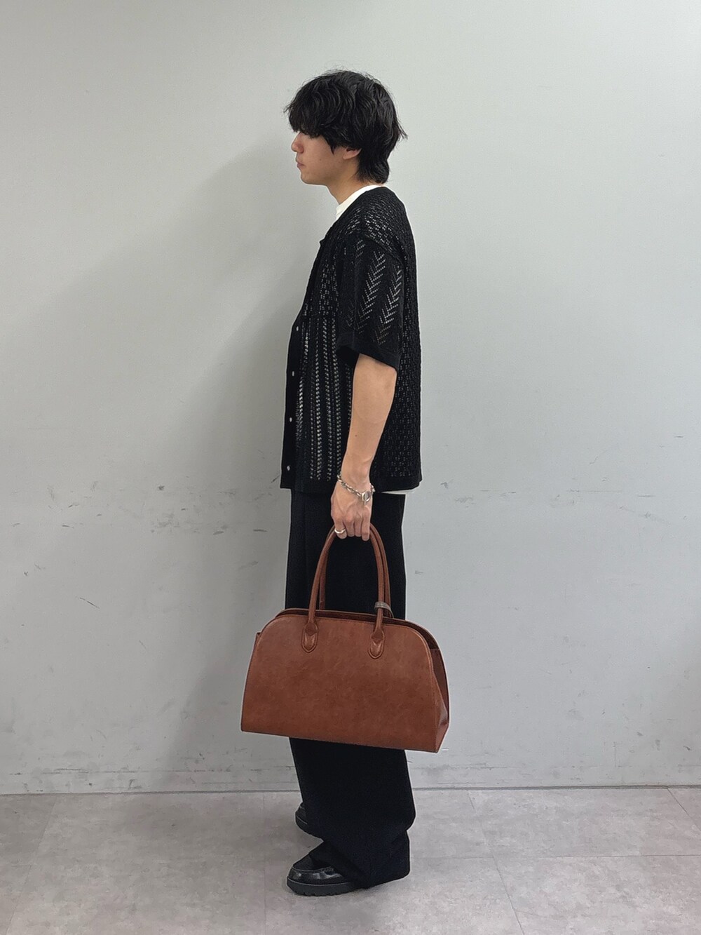 ブラック系のカーディガン/ボレロ、ブラック系のスラックス、イエロー系のトートバッグを着用したメンズの春コーディネートの2枚目の写真