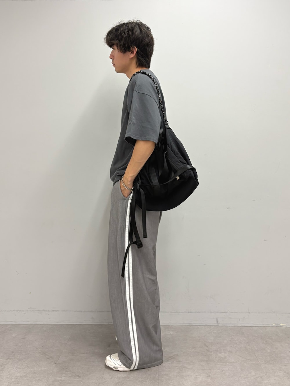 グレー系のTシャツ/カットソー、ブラック系のトートバッグ、グレー系のスラックスを着用したメンズの夏コーディネートの2枚目の写真