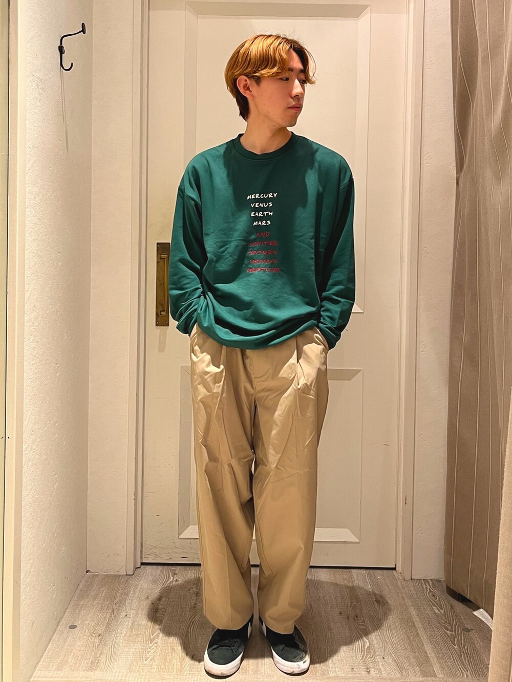 ブラック系のスニーカー、グリーン系のTシャツ/カットソー、ベージュ系のパンツを着用したメンズの夏コーディネートの2枚目の写真