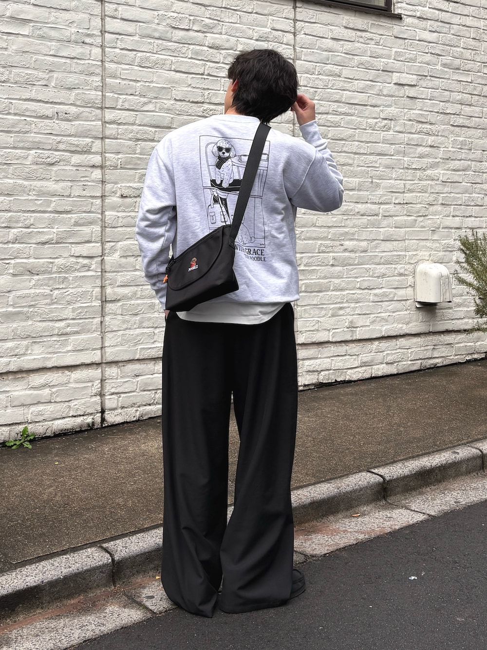 グレー系のスウェット、ブラック系のショルダーバッグ、ブラック系のスラックスを着用したメンズの冬コーディネートの2枚目の写真