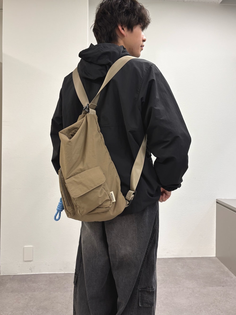 ブラック系のマウンテンパーカー、ブラック系のカーゴパンツ、ベージュ系のトートバッグを着用したメンズの春コーディネートの3枚目の写真