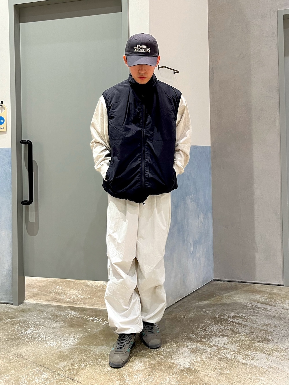 グレー系のスニーカー、グレー系のカーゴパンツ、ブラック系のベストを着用したメンズの冬コーディネートの2枚目の写真