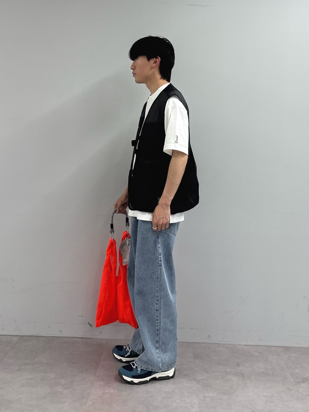 ホワイト系のTシャツ/カットソー、ブラック系のベスト、オレンジ系のトートバッグを着用したメンズの春コーディネートの2枚目の写真