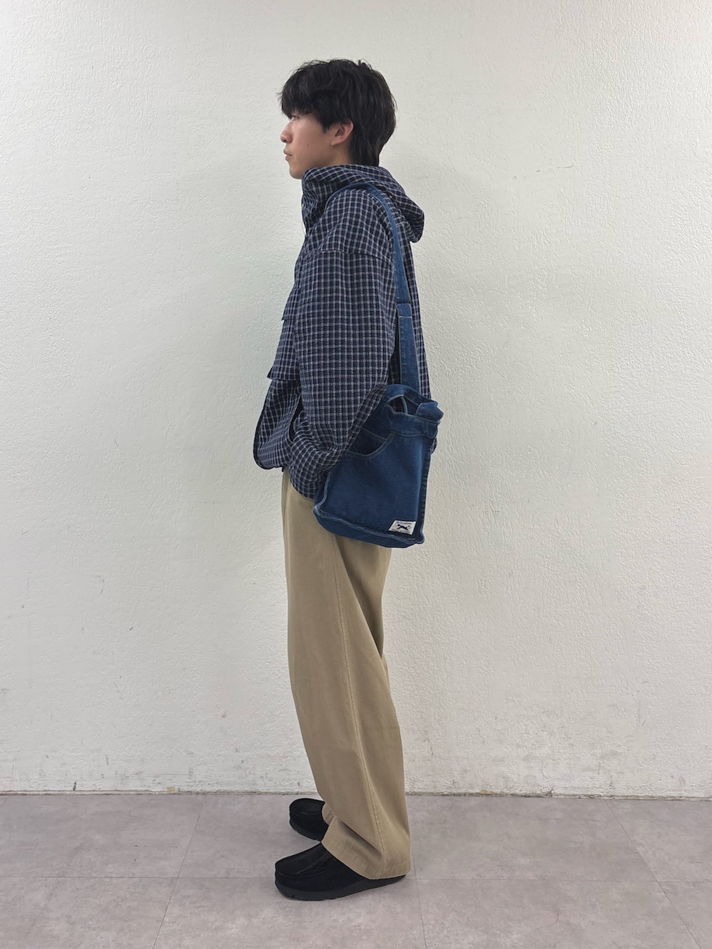 ベージュ系のチノパンツ、ブルー系のパーカー、ブルー系のショルダーバッグを着用したメンズの春コーディネートの2枚目の写真