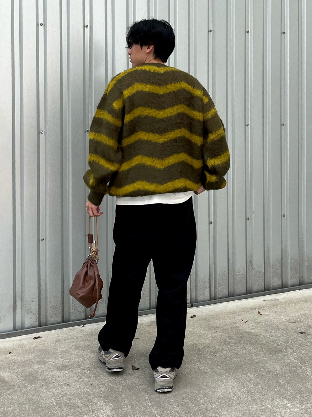 グレー系のスニーカー、グリーン系のニット/セーター、ブラック系のチノパンツを着用したメンズの秋コーディネートの2枚目の写真