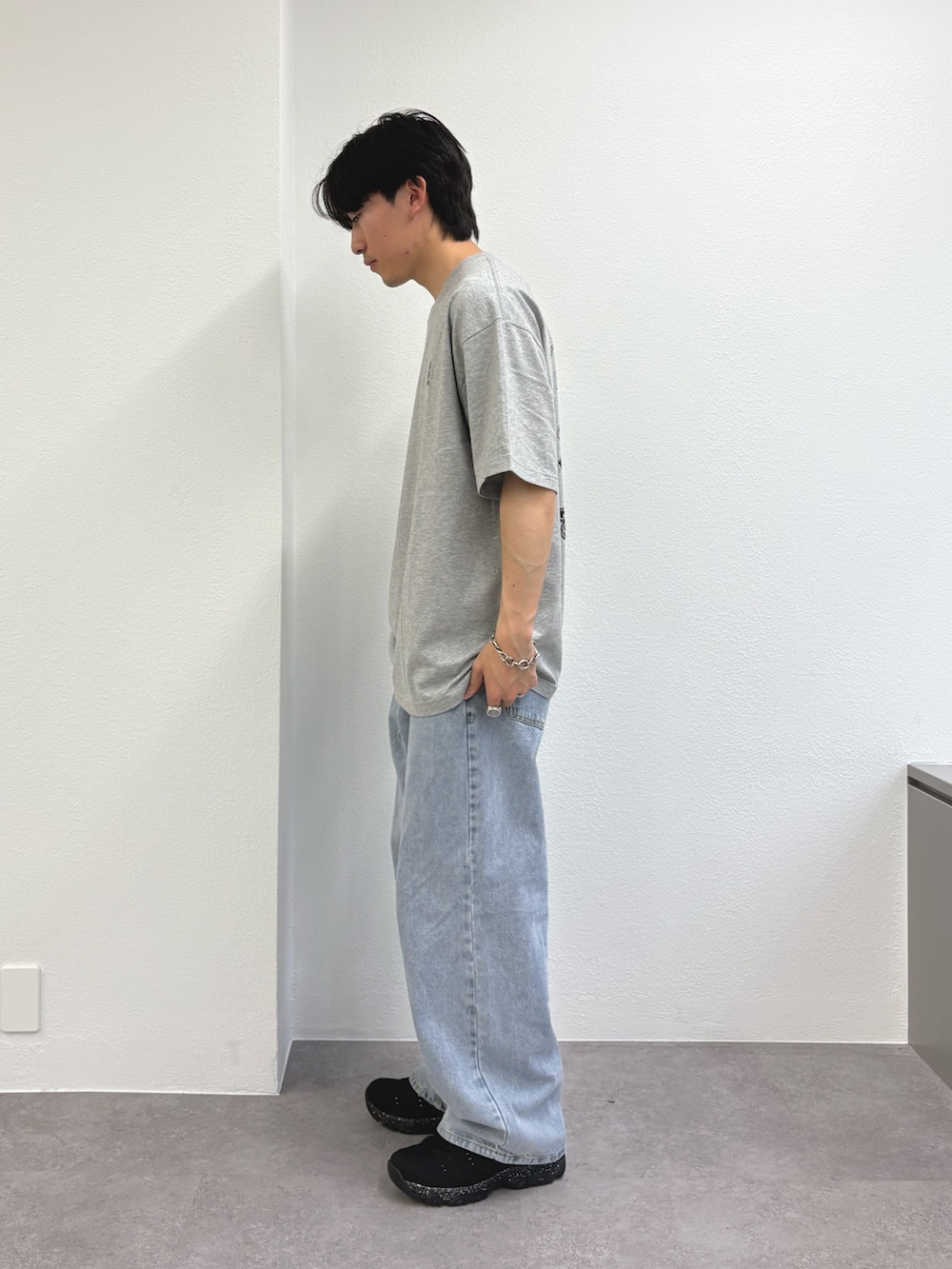 グレー系のTシャツ/カットソー、ブルー系のデニムパンツ、ブラック系のスニーカーを着用したメンズの春コーディネートの3枚目の写真