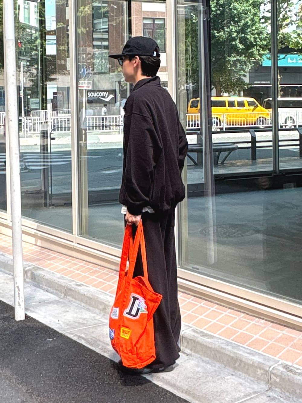 ブラック系のスウェット、ホワイト系のTシャツ/カットソー、オレンジ系のトートバッグを着用したメンズの夏コーディネートの3枚目の写真