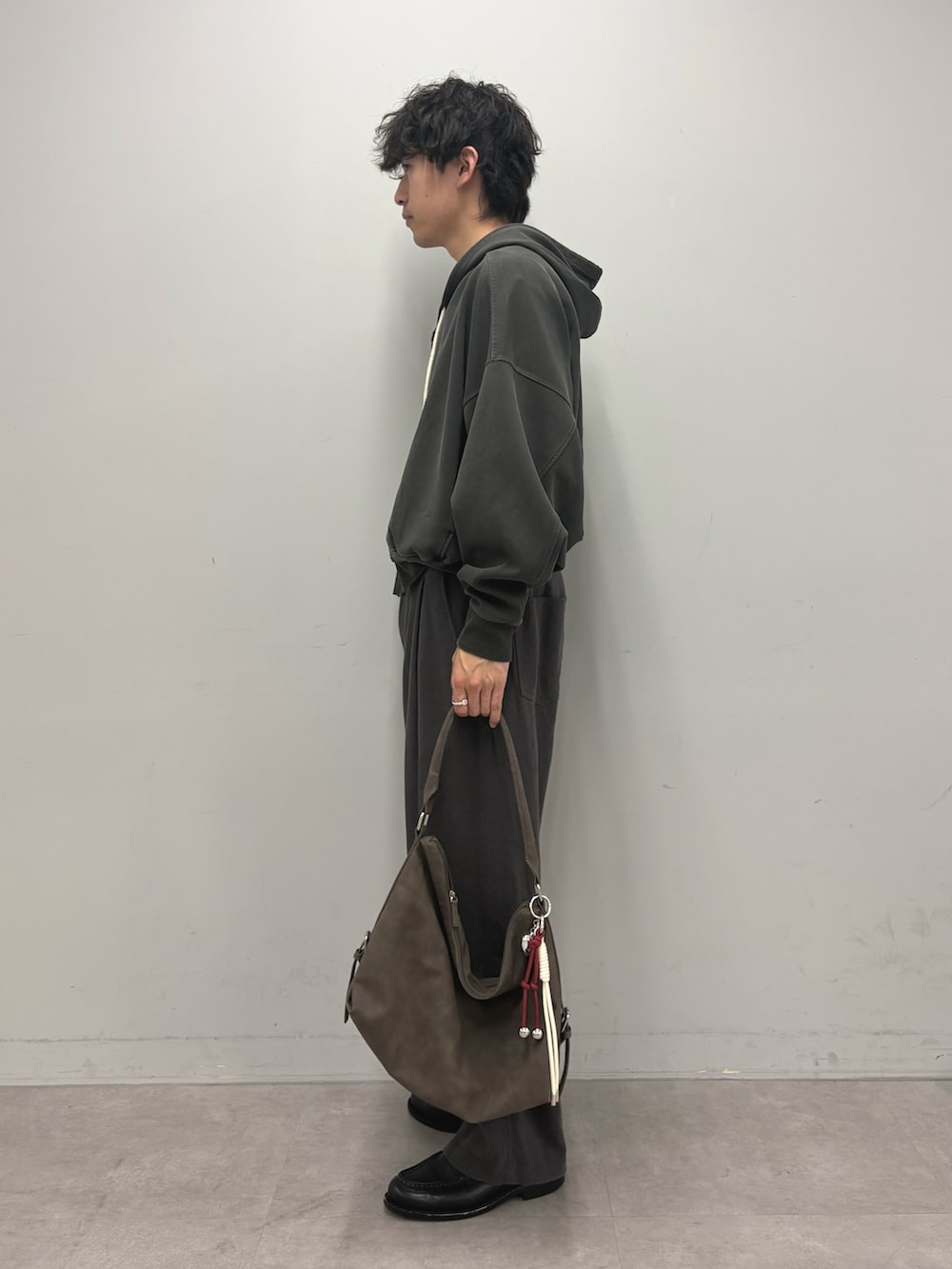 グレー系のパーカー、グレー系のその他パンツ、ブラウン系のトートバッグを着用したメンズの春コーディネートの2枚目の写真