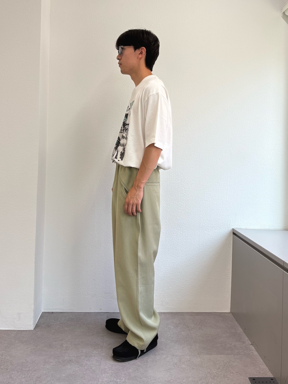 ホワイト系のTシャツ/カットソー、グリーン系のスラックスを着用したメンズの夏コーディネートの2枚目の写真