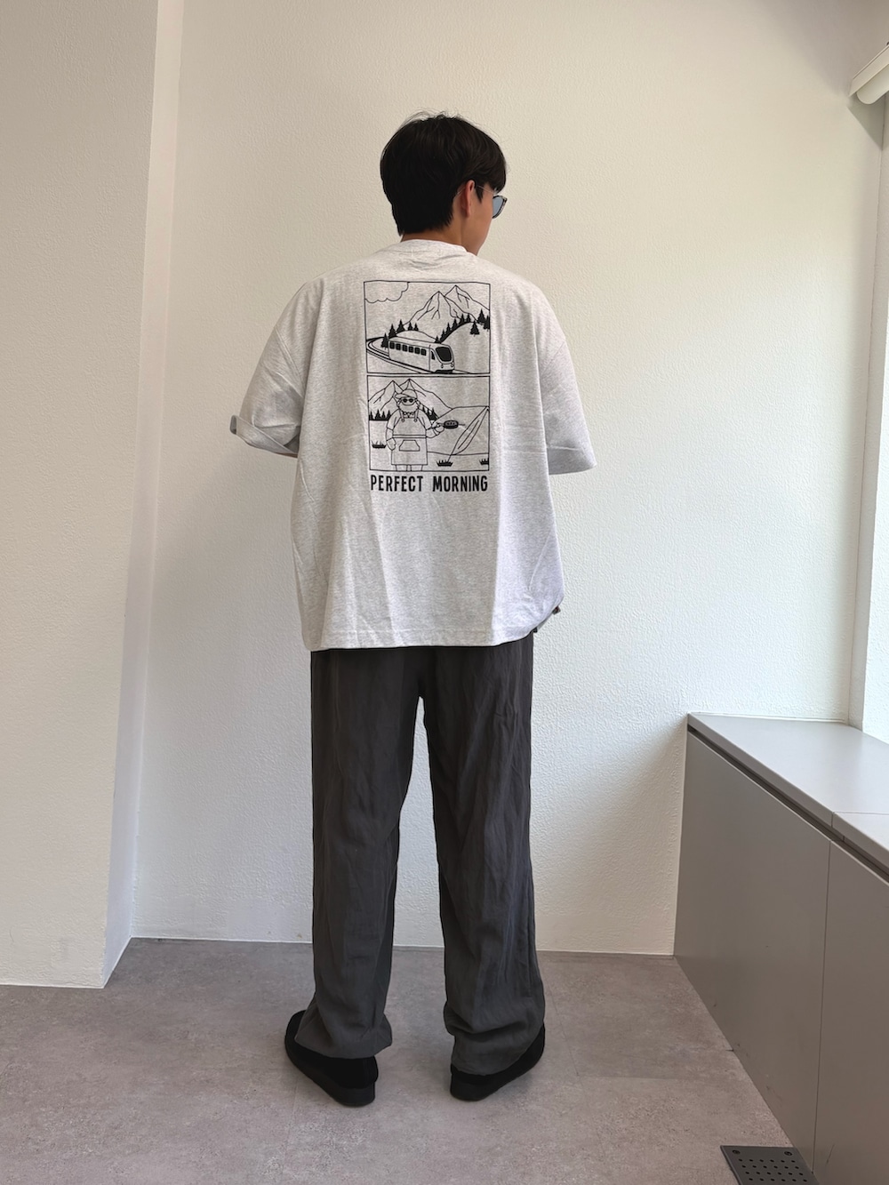 ホワイト系のTシャツ/カットソー、グレー系のスラックスを着用したメンズの夏コーディネートの3枚目の写真