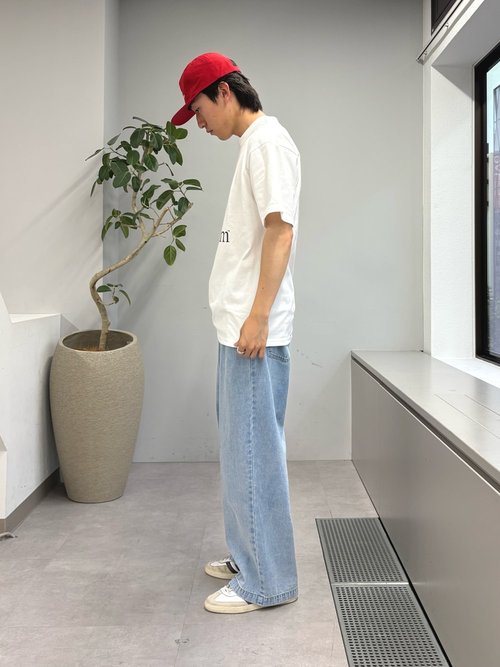 ホワイト系のTシャツ/カットソー、ブルー系のデニムパンツ、レッド系のキャップを着用したメンズの春コーディネートの2枚目の写真