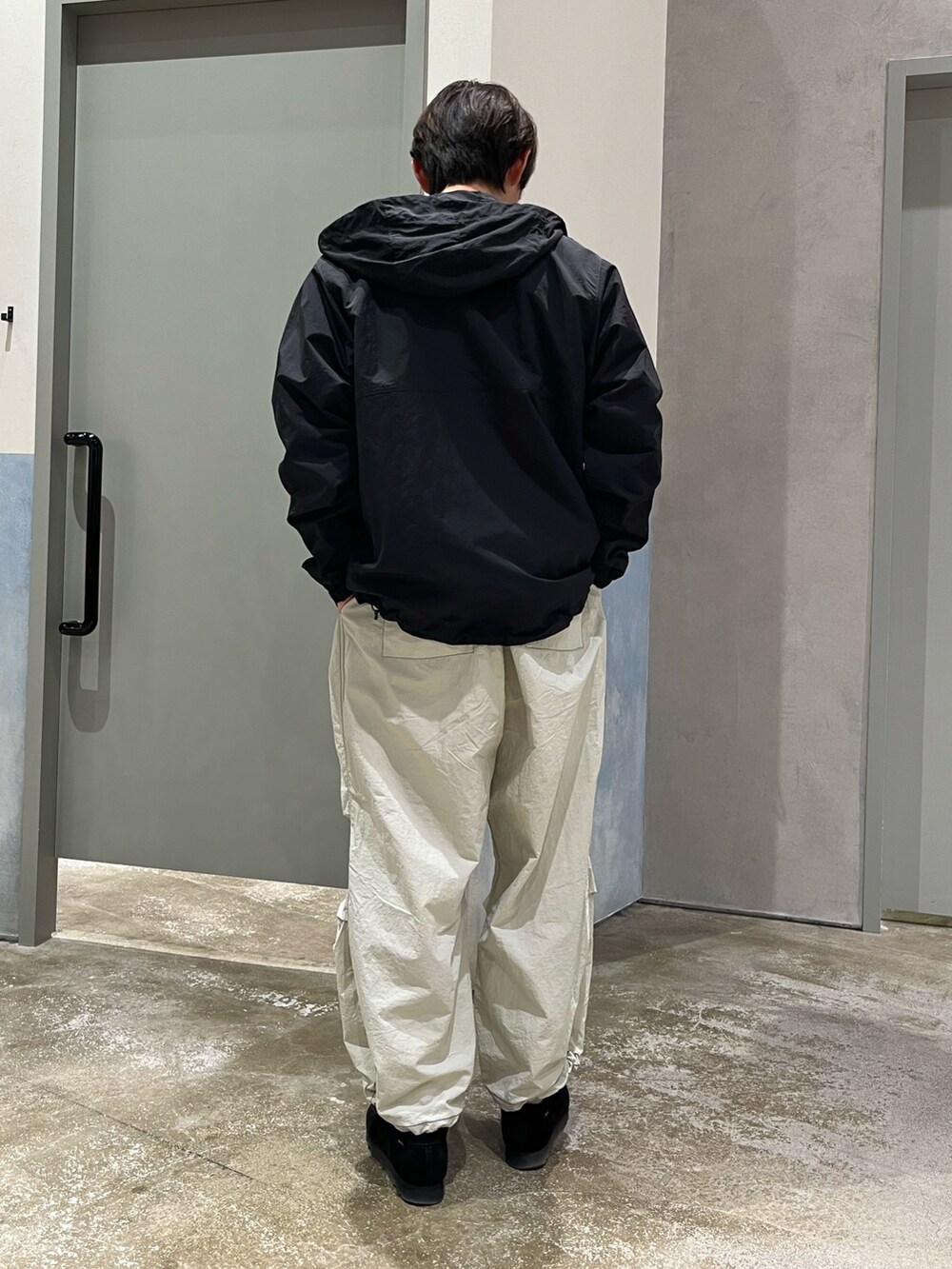 ブラック系のスニーカー、グレー系のカーゴパンツ、ブラック系のマウンテンパーカーを着用したメンズの春コーディネートの3枚目の写真