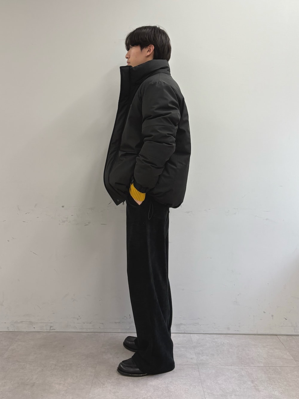 ブラック系のダウンジャケット/コート、イエロー系のニット/セーター、ブラック系のその他パンツを着用したメンズの冬コーディネートの2枚目の写真