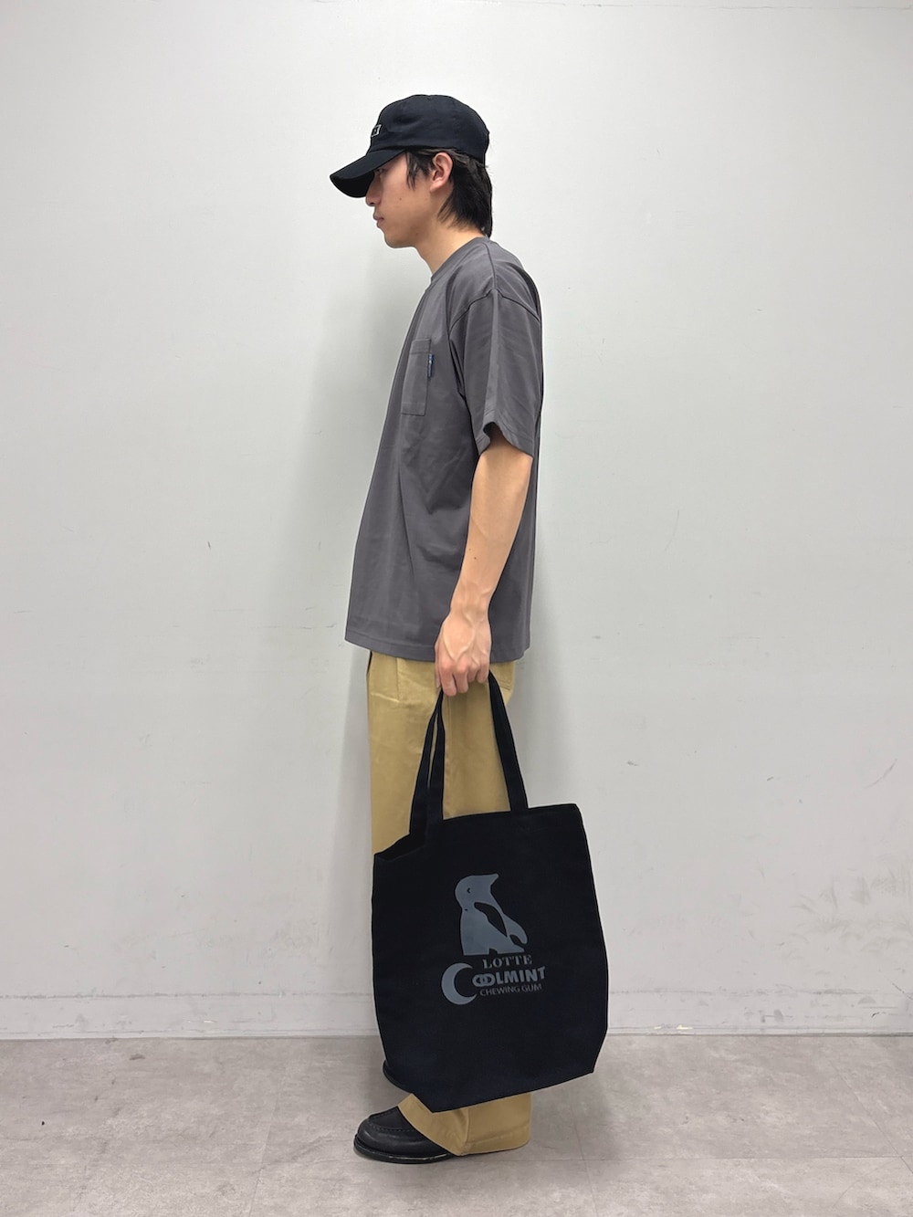 グレー系のTシャツ/カットソー、ベージュ系のデニムパンツ、ブラック系のトートバッグを着用したメンズの春コーディネートの2枚目の写真