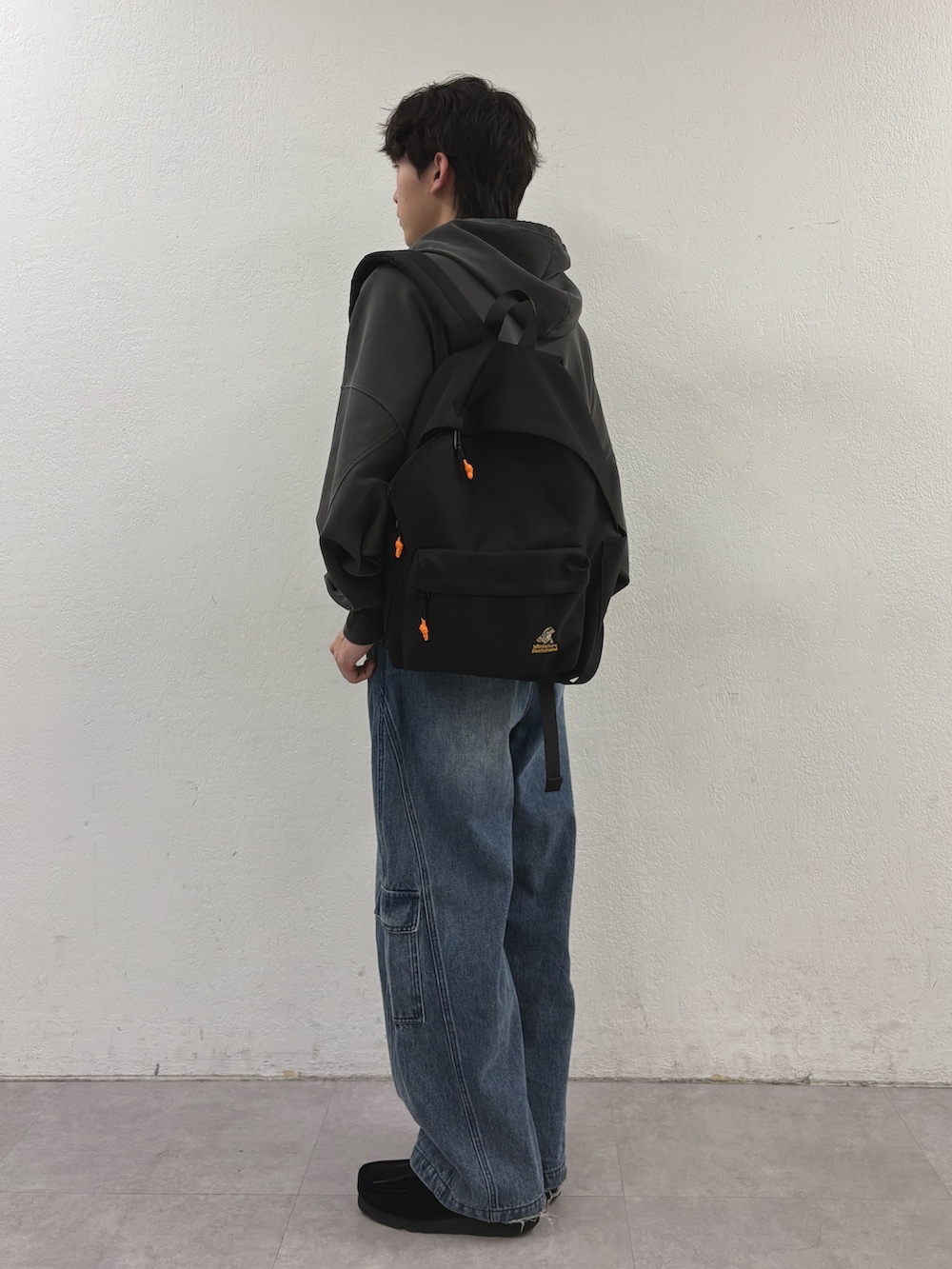 グレー系のパーカー、ブラック系のバックパック/リュック、ブルー系のカーゴパンツを着用したメンズの春コーディネートの2枚目の写真