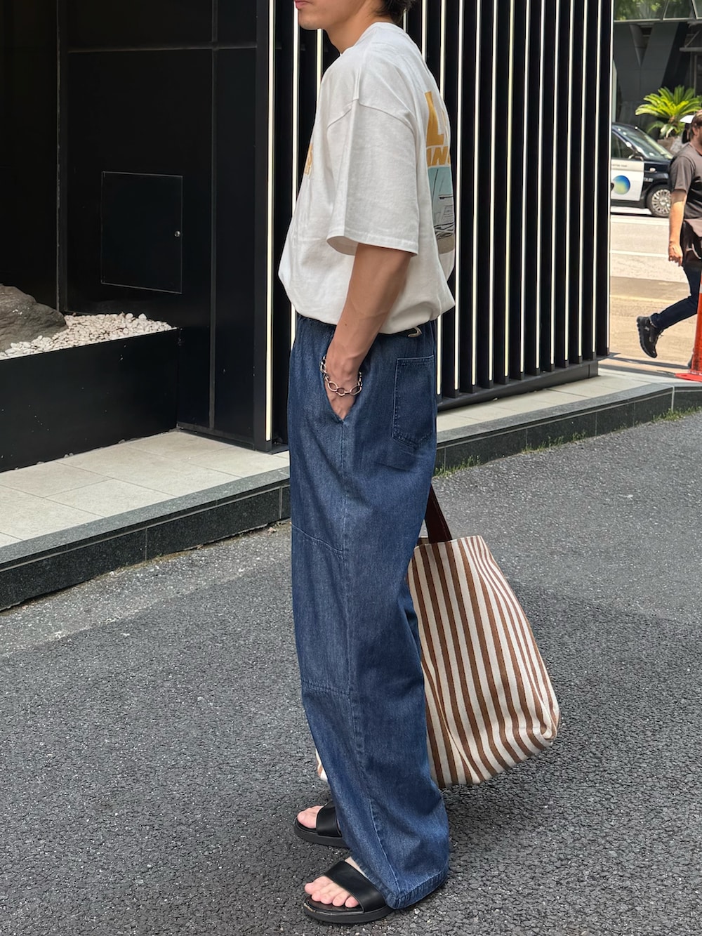 ホワイト系のTシャツ/カットソー、ブルー系のデニムパンツ、イエロー系のトートバッグを着用したメンズの春コーディネートの2枚目の写真