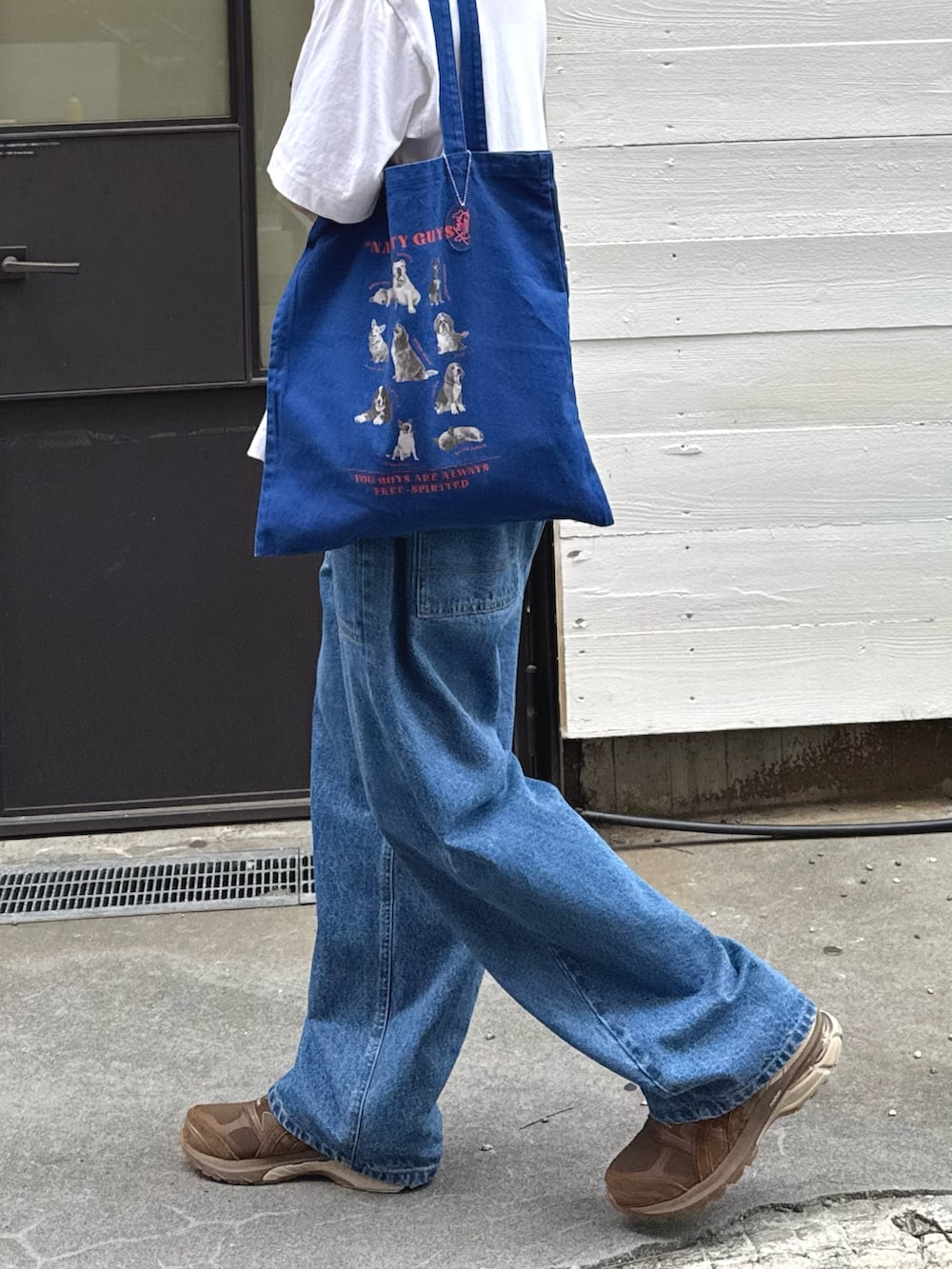 ホワイト系のTシャツ/カットソー、ブルー系のトートバッグ、ブルー系のデニムパンツを着用したメンズの夏コーディネートの3枚目の写真