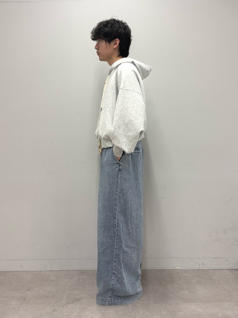 グレー系のパーカー、ブルー系のデニムパンツを着用したメンズの春コーディネートの2枚目の写真