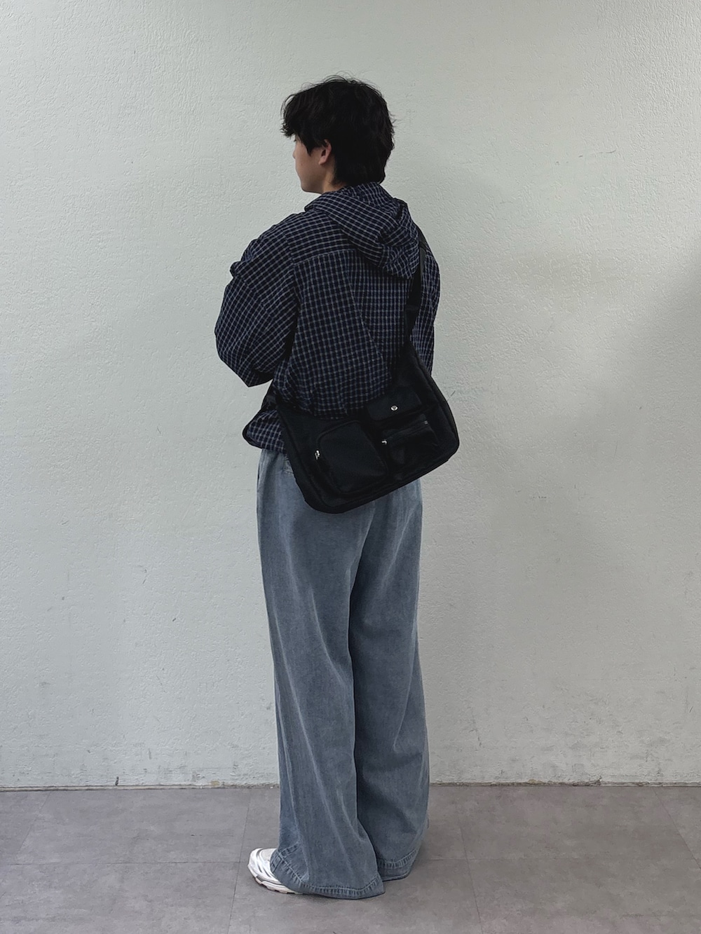 ブルー系のパーカー、ブラック系のショルダーバッグ、ブルー系のデニムパンツを着用したメンズの春コーディネートの2枚目の写真