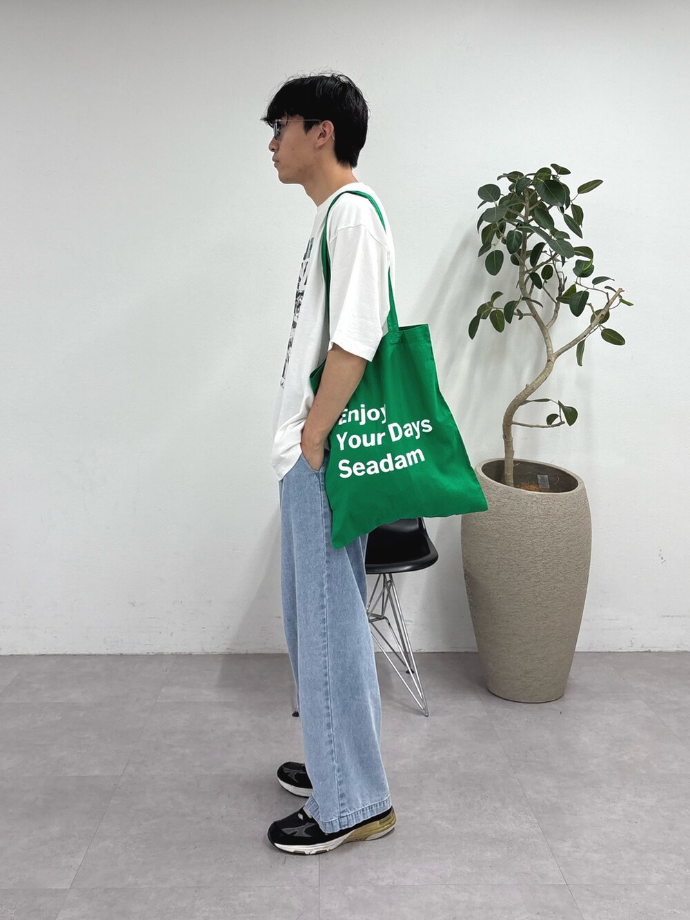 ホワイト系のTシャツ/カットソー、ブルー系のデニムパンツ、グリーン系のトートバッグを着用したメンズの夏コーディネートの2枚目の写真