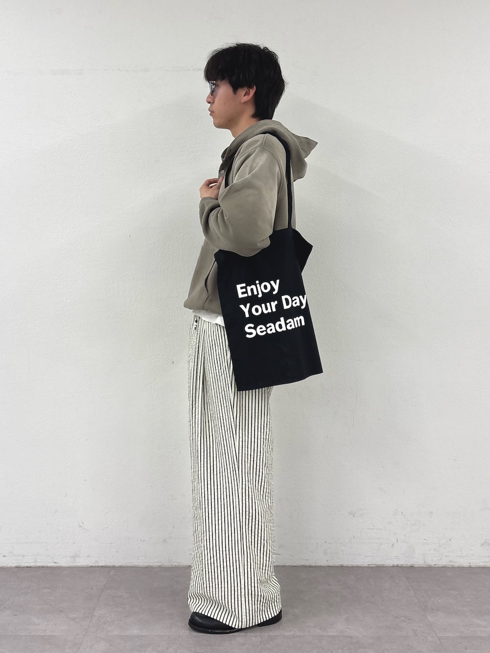 ベージュ系のパーカー、ホワイト系のその他パンツ、ブラック系のトートバッグを着用したメンズの春コーディネートの2枚目の写真