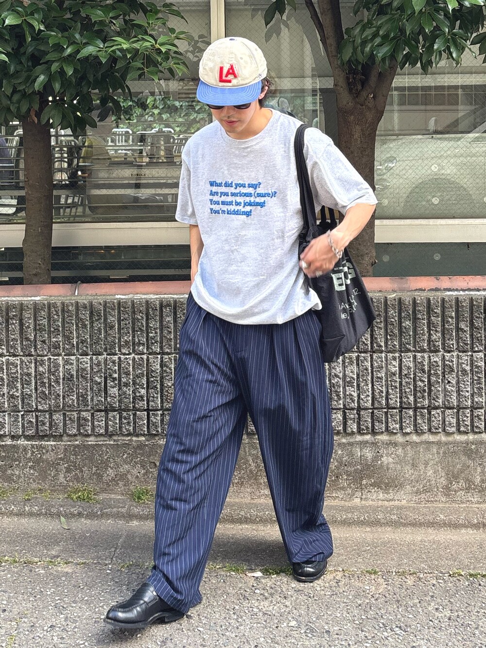 グレー系のTシャツ/カットソー、ブルー系のスラックス、ブラック系のトートバッグを着用したメンズの春コーディネートの2枚目の写真