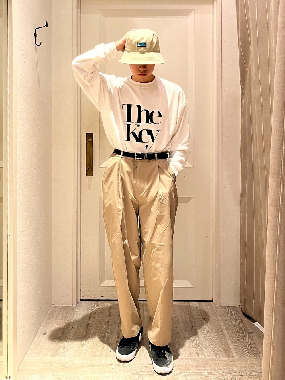 ブラック系のスニーカー、ベージュ系のパンツ、ホワイト系のTシャツ/カットソーを着用したメンズの夏コーディネートの2枚目の写真