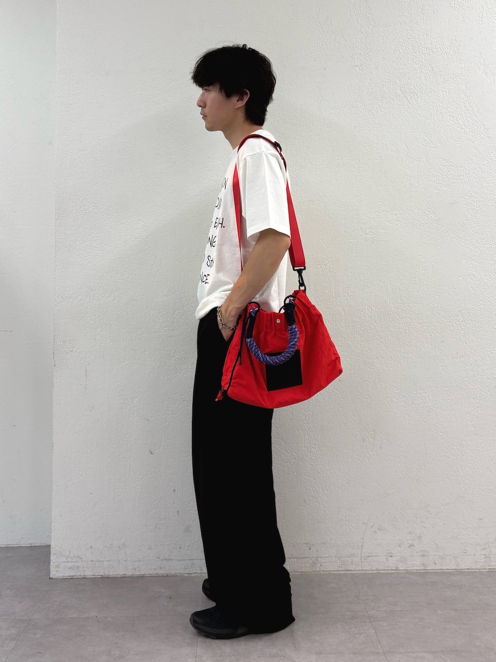 ホワイト系のTシャツ/カットソー、レッド系のトートバッグ、ブラック系のスラックスを着用したメンズの夏コーディネートの2枚目の写真