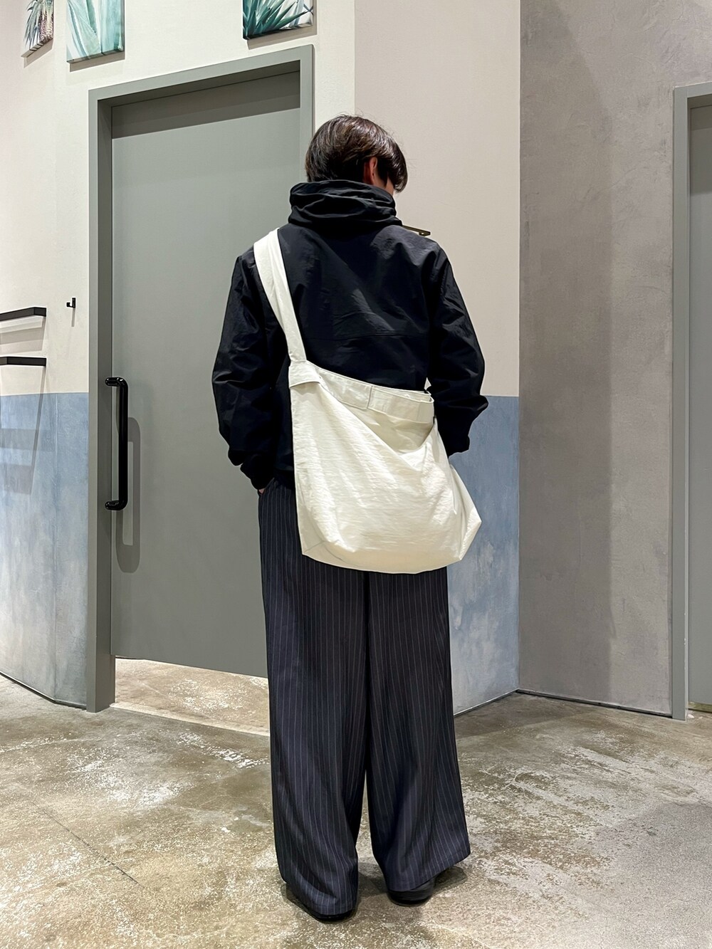 ブラック系のスニーカー、ブラック系のマウンテンパーカー、ホワイト系のショルダーバッグを着用したメンズの春コーディネートの2枚目の写真