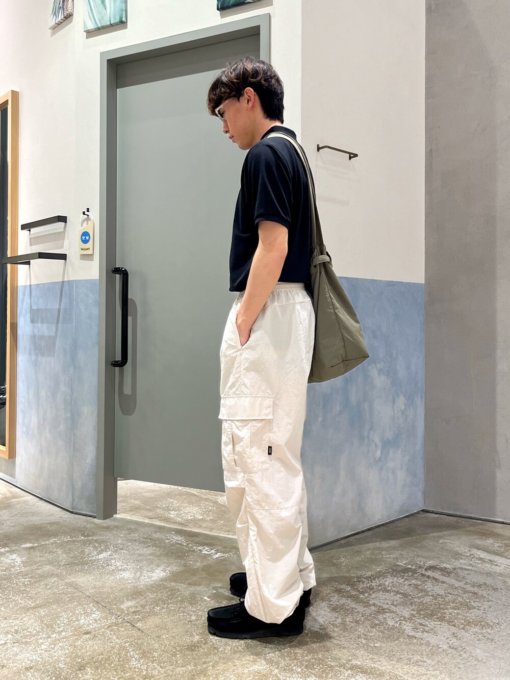 ブラック系のスニーカー、ホワイト系のカーゴパンツ、ブラック系のポロシャツを着用したメンズの春コーディネートの2枚目の写真